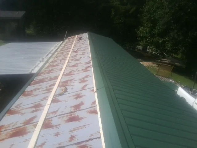 Old rusted panels beside newly installed green metal roofing — Wind Damage Roof Repair by Roofing Brothers in Lake Worth