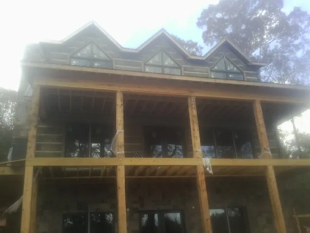 Dormers and porch framing on a large log home under construction — Roof Coating work by our crew in Lake Worth