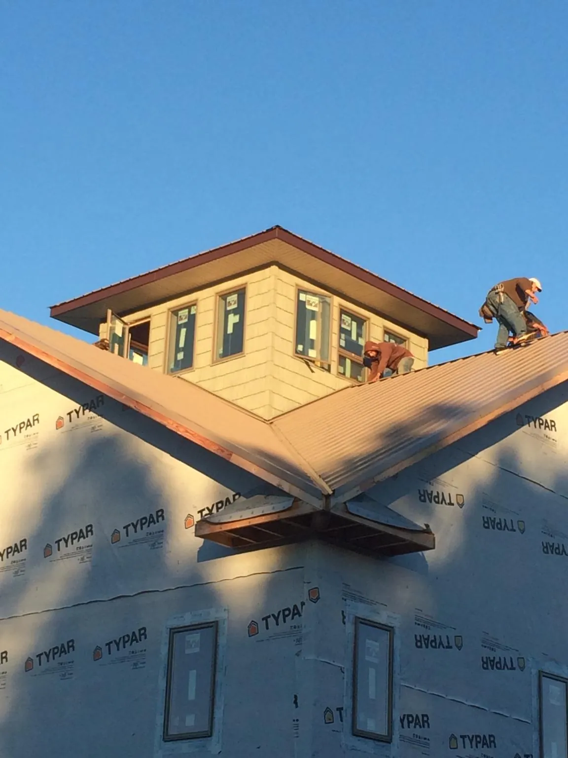 Roofers working around a rooftop cupola on a new metal roof at sunset — Roof Waterproofing in Lake Worth by Roofing Brothers